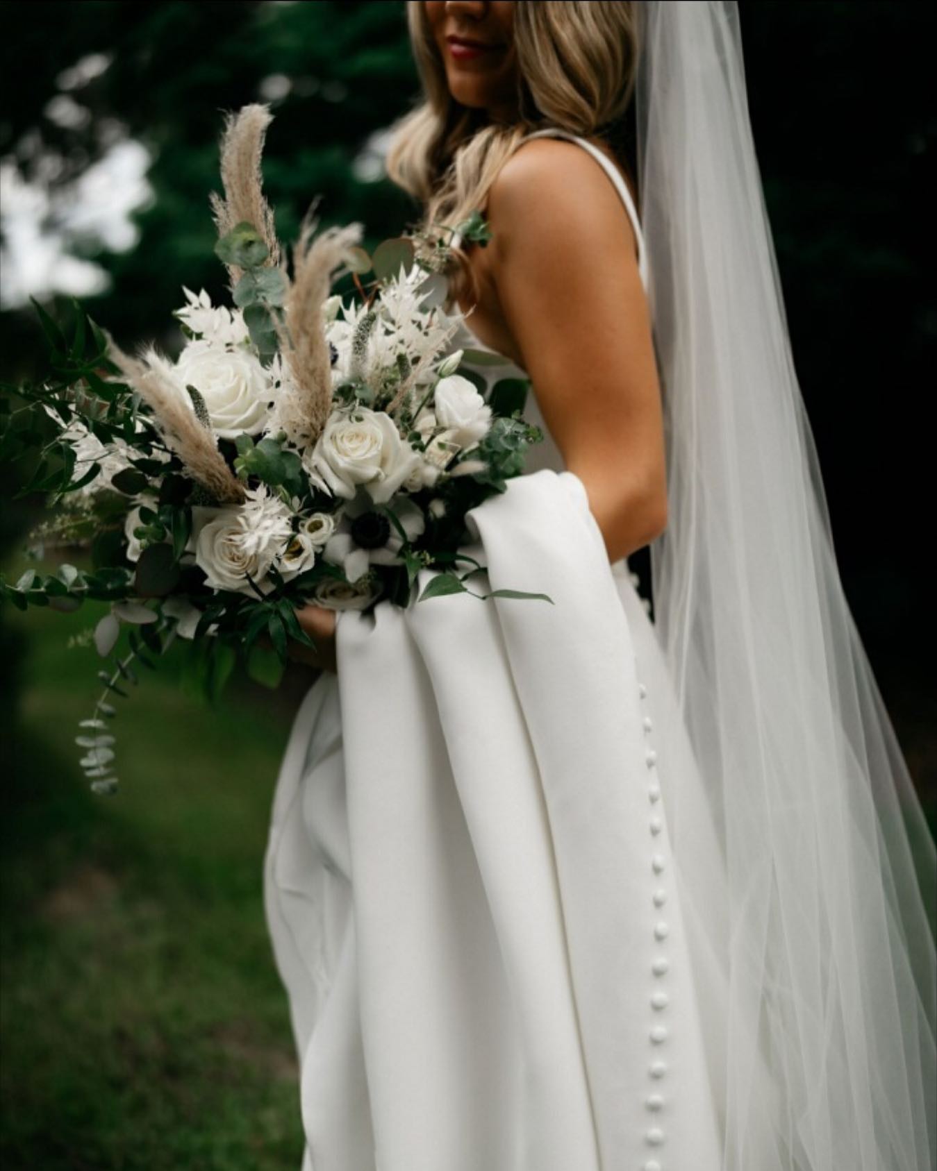 About 1 bride posing with white roses outdoors